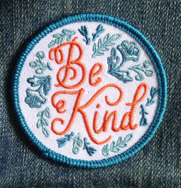 Circular patch with 'Be Kind' text on a denim background
